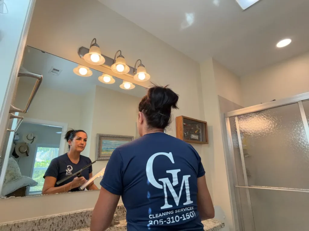 Cleaning Services GM crew member sanitizing a bathroom mirror during a same-day vacation rental turnover in the Florida Keys