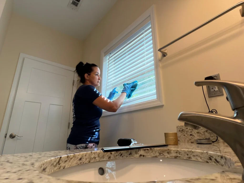 Cleaning Services GM team member dusting window blinds during a deep cleaning in the Florida Keys