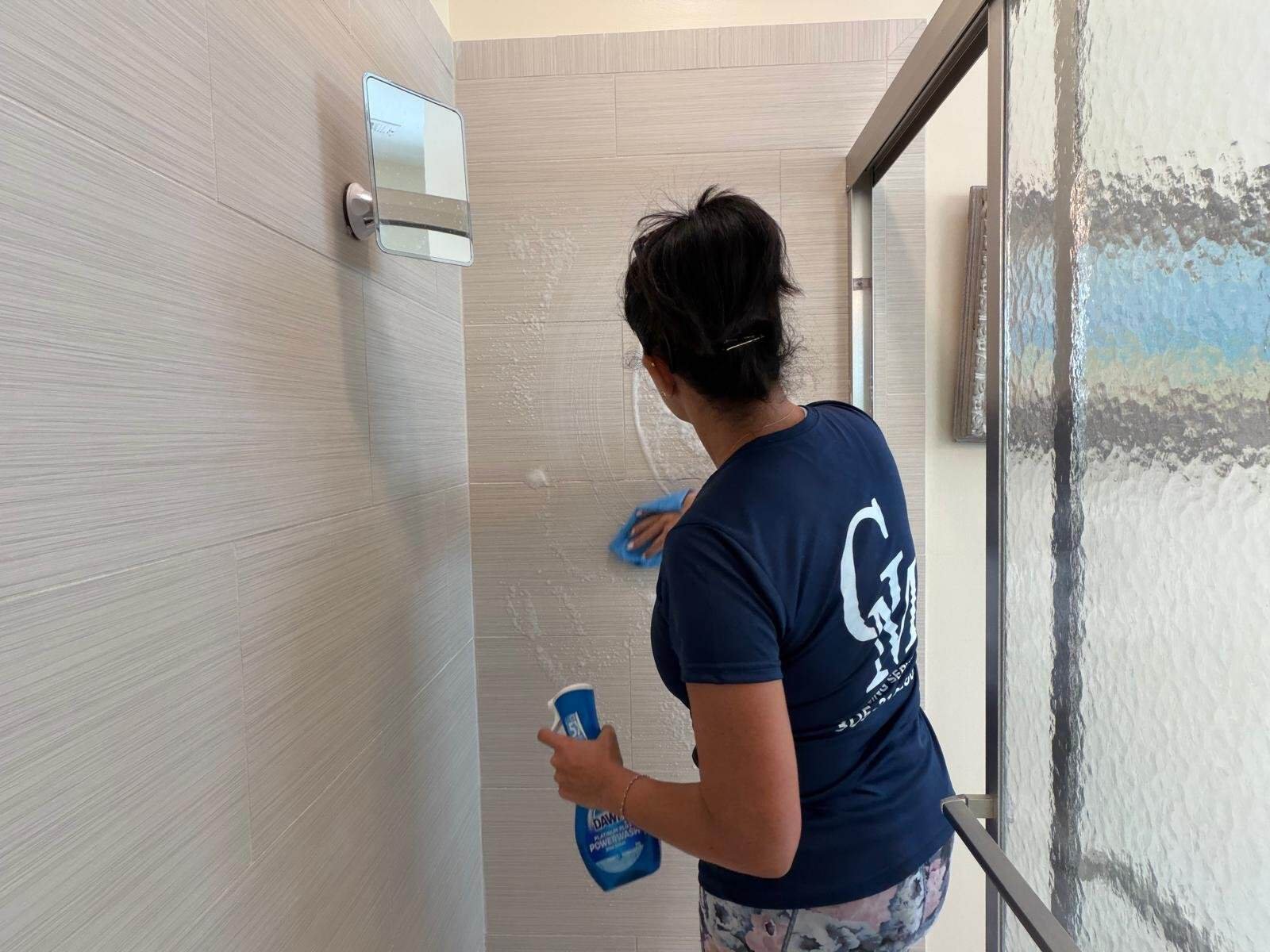 Cleaning Services GM crew member deep cleaning a bathroom shower wall in a Florida Keys home