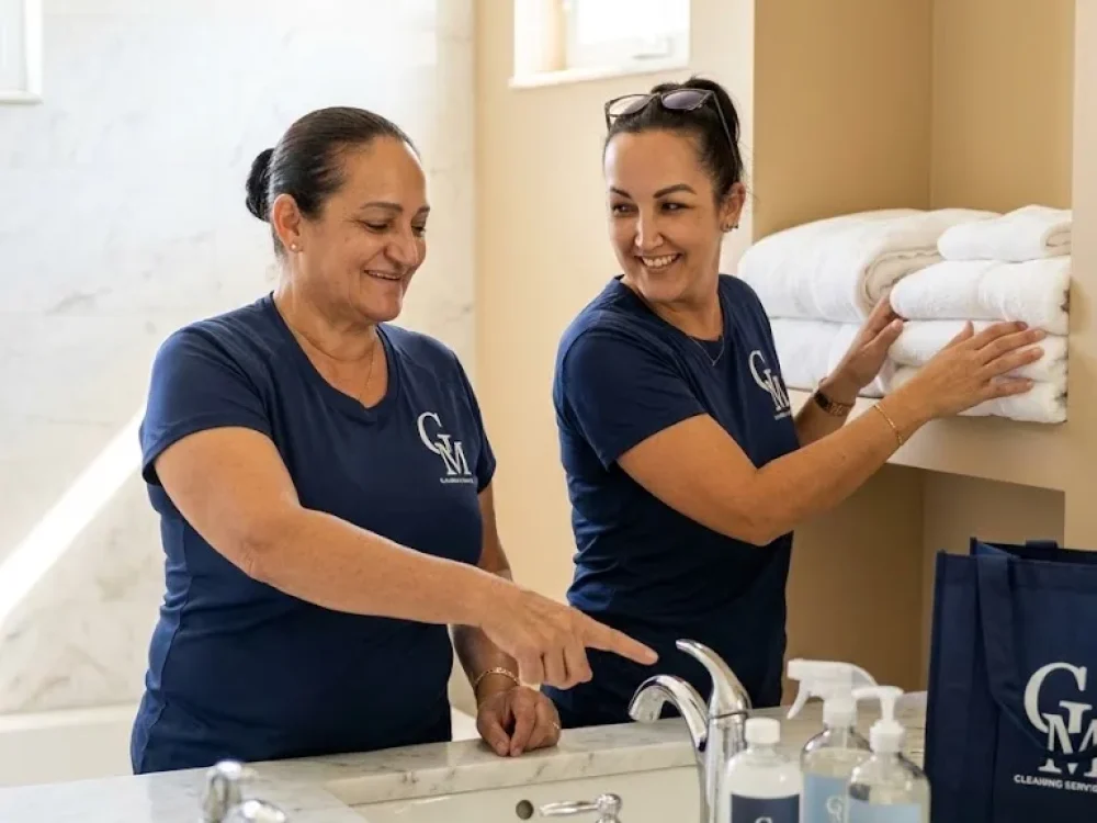 vacation-rental-cleaning-crew-florida-keys Two Cleaning Services GM team members restocking fresh towels and cleaning supplies in a Florida Keys vacation rental bathroom during a turnover clean